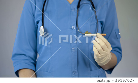 Female doctor holding cigarette in hand, cancer Female doctor holding cigarette in hand, cancer 39197027