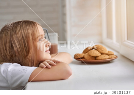 Dreamy girl with cookies on window sill. 39201137