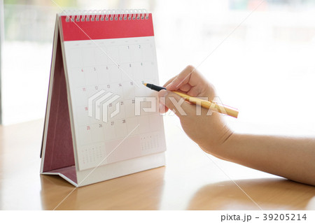 Woman hand carrying calendar and pointing on it by 39205214