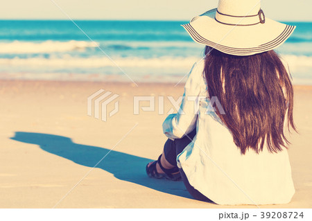 Woman in a hat sitting on the beach 39208724