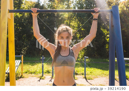 Young beautiful girl doing chin-ups on the outdoor 39214190