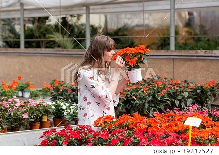 Lovely happy young woman gardener choosing flower Lovely happy young woman gardener choosing flower 39217527