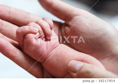 Female hand holding newborn baby's hand. 39217954
