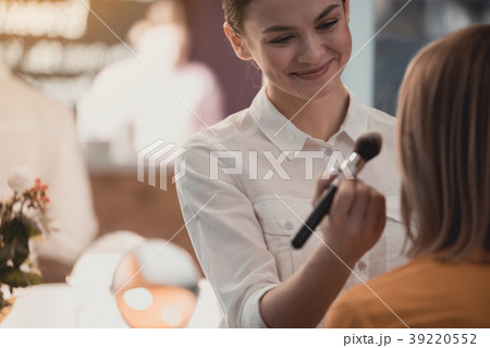 Cheerful woman applying make-up for visitor 39220552