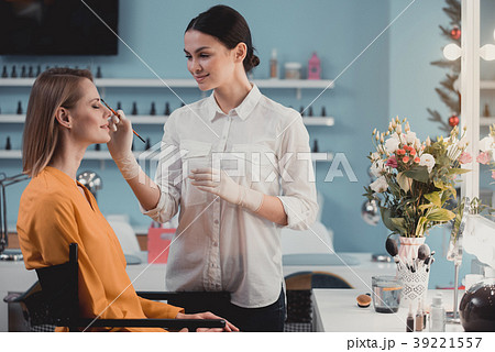 Happy cosmetologist doing make-up for happy 39221557