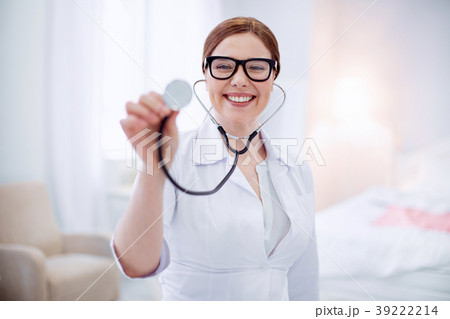 Optimistic female doctor demonstrating stethoscope Optimistic female doctor demonstrating stethoscope 39222214