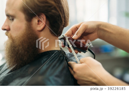 Bearded man having a haircut with a hair clippers Bearded man having a haircut with a hair clippers 39226185