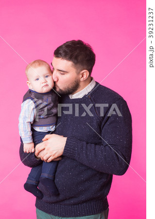 Happy father holding baby son in hands over pink Happy father holding baby son in hands over pink 39231237