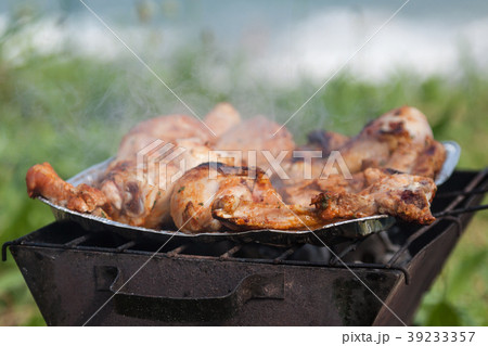 Grilled chicken thighs on the flaming grill. 39233357