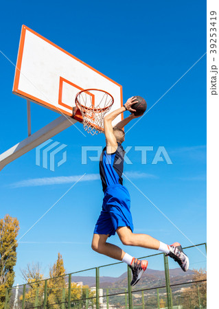 Young Basketball street player making slam dunk Young Basketball street player making slam dunk 39253419
