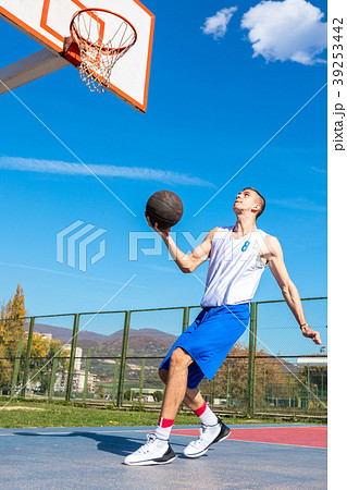 Young Basketball street player making slam dunk 39253442