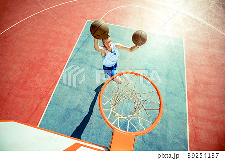 Young man jumping and making a fantastic slam dunk Young man jumping and making a fantastic slam dunk 39254137