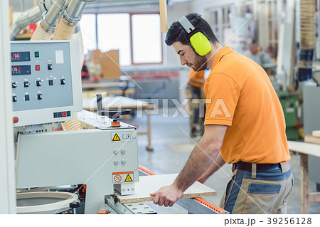 Carpenter working in furniture factory on machine Carpenter working in furniture factory on machine 39256128