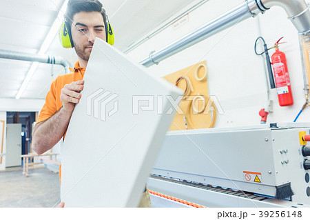 Carpenter in furniture factory working on veneer 39256148