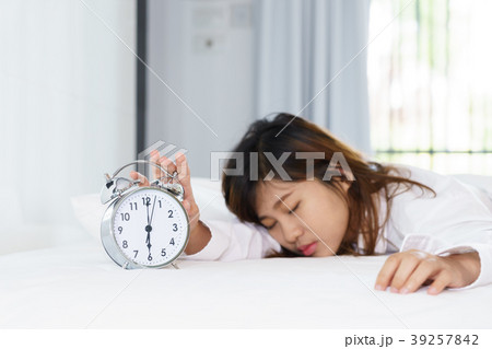 Sleepy woman trying turn off alarm clock Sleepy woman trying turn off alarm clock 39257842