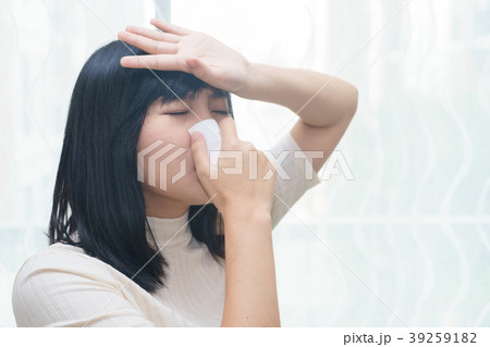 Woman with allergy or cold sneezing into napkin Woman with allergy or cold sneezing into napkin 39259182