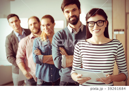 Smart cheerful woman standing in front of her team 39261684