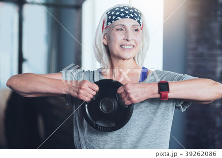Beaming senior lady lifting kettle bell in gym 39262086