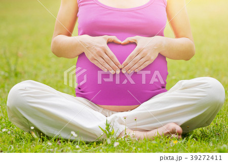 Pregnant woman holding her hands in a heart shape 39272411