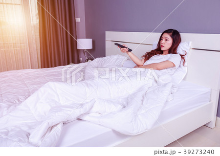 woman lying on a bed with remote control  39273240