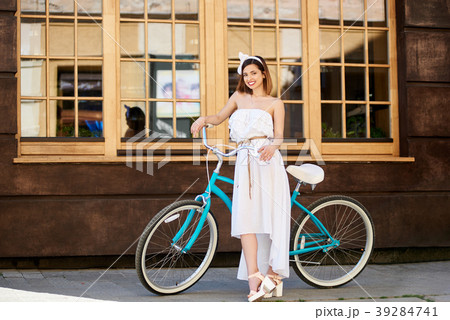 Pretty girl posing near turquoise bike in front of a cafe Pretty girl posing near turquoise bike in front of a cafe 39284741