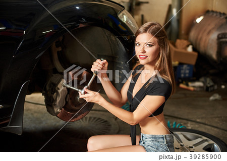 Close-up of girl is sitting on tire near black car Close-up of girl is sitting on tire near black car 39285900