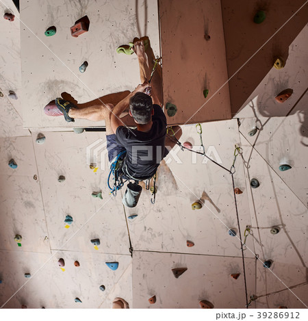 man practicing rock-climbing on rock wall indoors man practicing rock-climbing on rock wall indoors 39286912