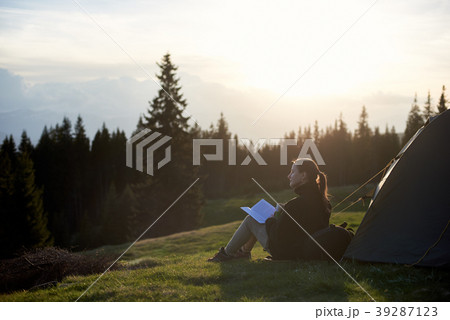 woman hiker with book near the tent in the evening 39287123