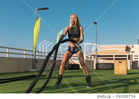 Sports woman doing battle ropes exercises in a Sports woman doing battle ropes exercises in a 39288754