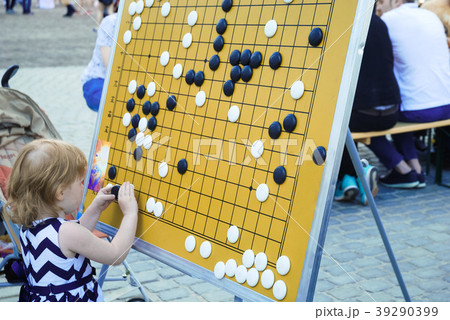 Little girl is playing on the board in checkers Go 39290399