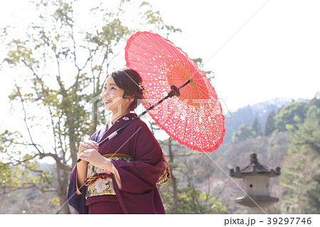 赤い和傘を持つ晴れ着の日本女性の写真素材