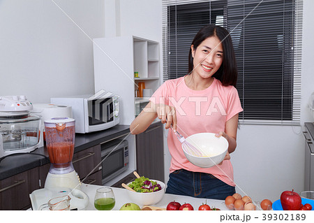 woman cooking and whisking eggs in a bowl in kitchen 39302189