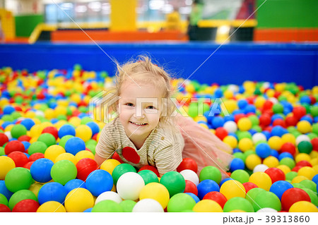 Curly little girl having fun in ball pit with colorful balls Curly little girl having fun in ball pit with colorful balls 39313860