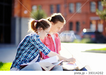 Young happy students with books and notes outdoors 39314202