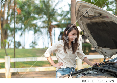 Young woman looking at her broken down car Young woman looking at her broken down car 39317379