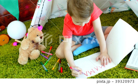 Little boy is writing MAMA in the drawing album in 39320973