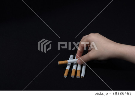 Hand is holding a cigarette on black background Hand is holding a cigarette on black background 39336465