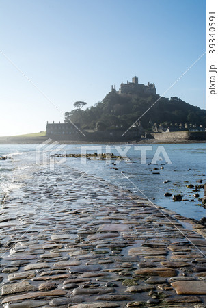 快晴の下に見えるセントマイケルズマウントと海岸と島に続く石畳の細道の写真素材