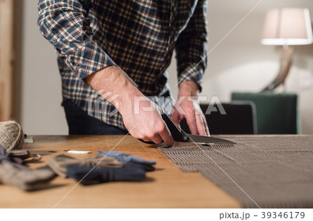Closeup cutting brown plaid wool fabric. the line 39346179