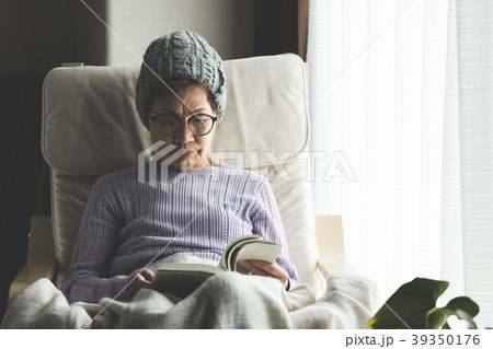窓際の椅子に座って本を読むシニア女性 窓際の椅子に座って本を読むシニア女性 39350176