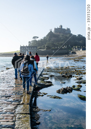 快晴の下に見えるセントマイケルズマウントと海岸と島に続く石畳の細道を歩く観光客 39355250