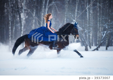 Young girl in dress riding horse on winter field 39373007