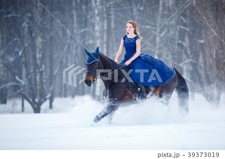 Young girl in dress riding horse on winter field 39373019