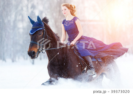 Young girl in dress riding horse on winter field 39373020
