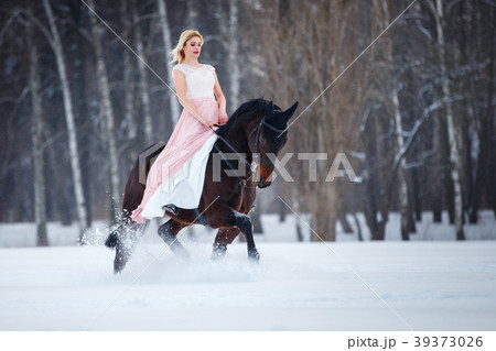 Young woman in dress riding horse on winter field 39373026