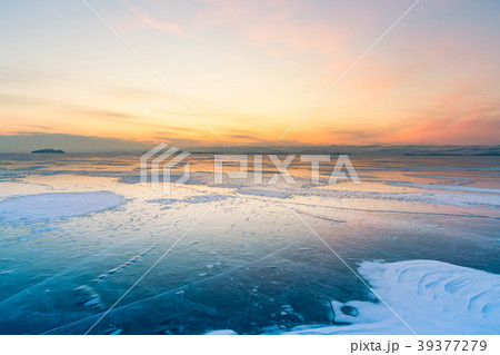 Sunrise sky over ice water lake with skyline Sunrise sky over ice water lake with skyline 39377279