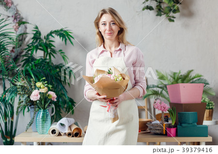 Portrait of smiling florist in apron with bouquet Portrait of smiling florist in apron with bouquet 39379416