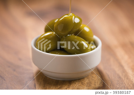 big green salted olives in white bowl on wooden 39380187