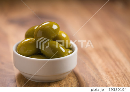 big green salted olives in white bowl on wooden 39380194
