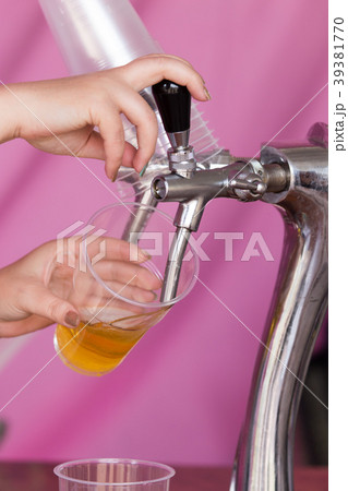 Barman pours beer into a plastic glass Barman pours beer into a plastic glass 39381770